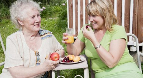 Older person and younger person eating fruit outside