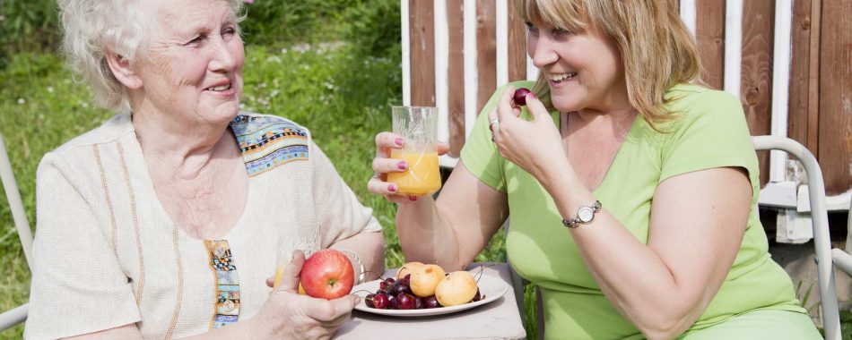 Older person and younger person eating fruit outside