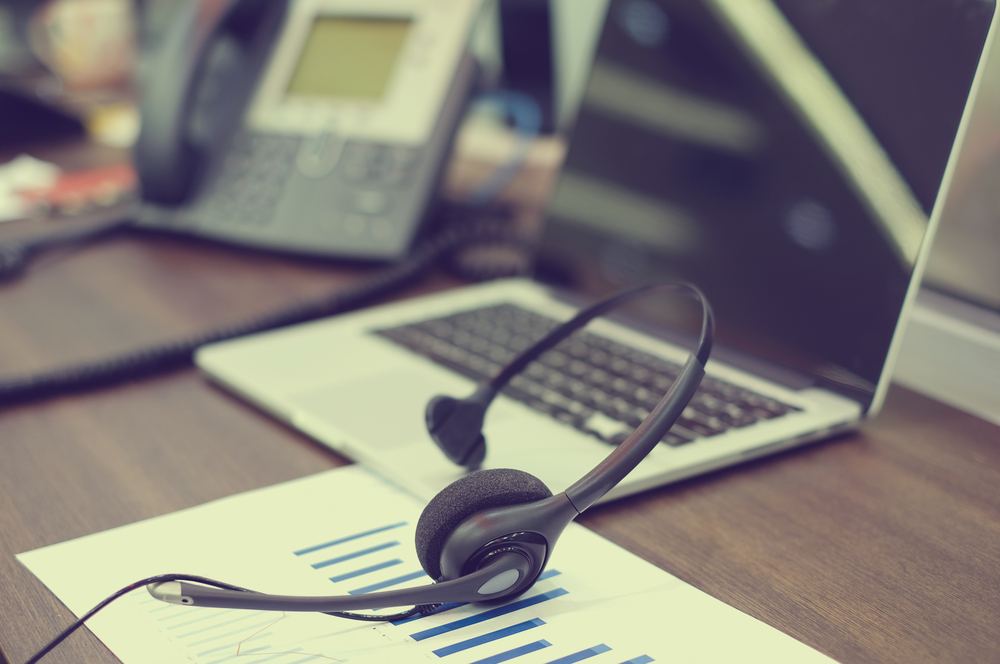 telephone headset, telephone and computer on a desk