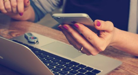 Person looking at phone sat at computer