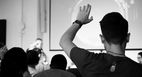 Photo of person in classroom raising hand