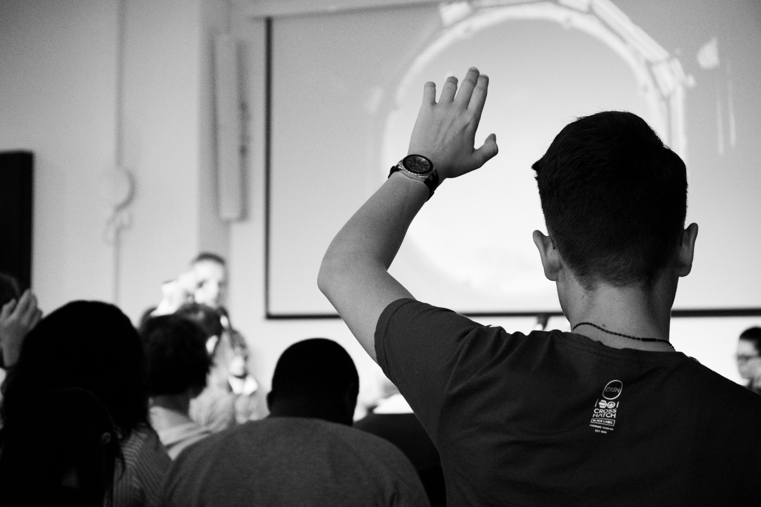 Photo of person in classroom raising hand