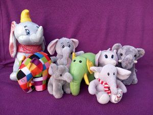 A cute group of stuffed elephant toys are on a purple cloth